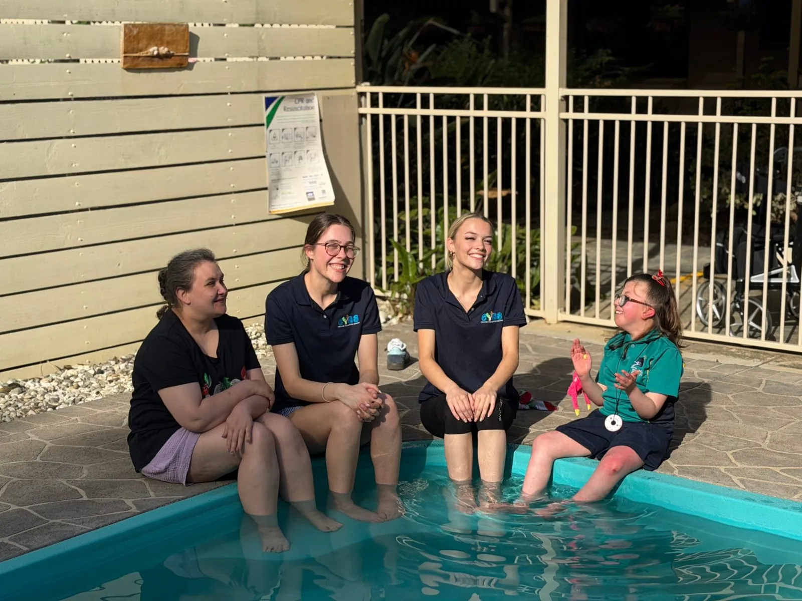Participants and EYSS support workers laughing with their feet in the pool