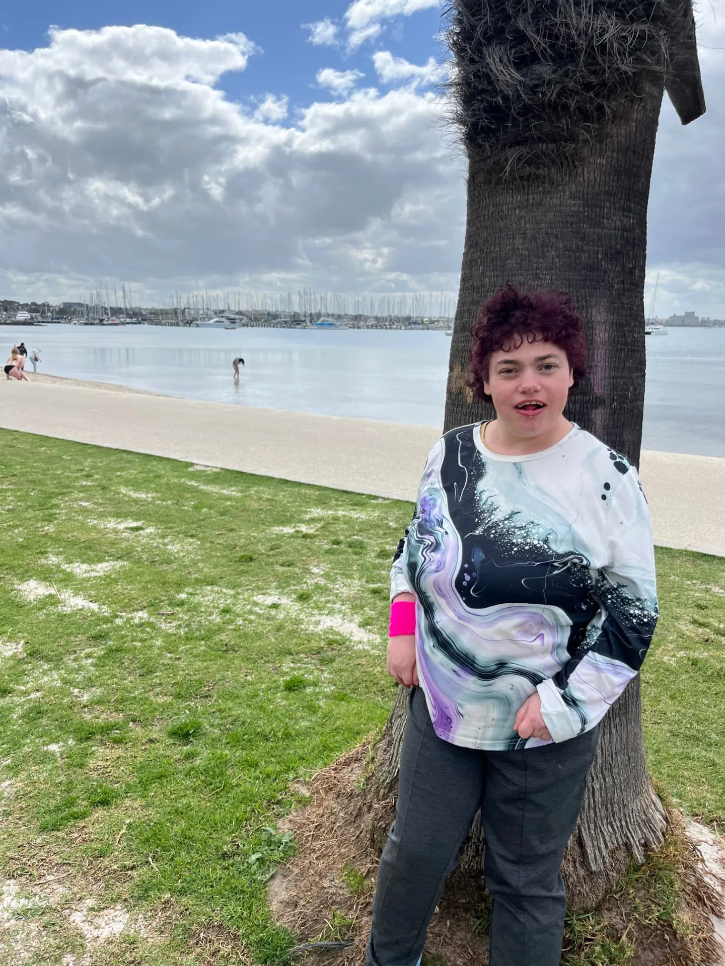 Participant standing by a palm tree with the bay behind
